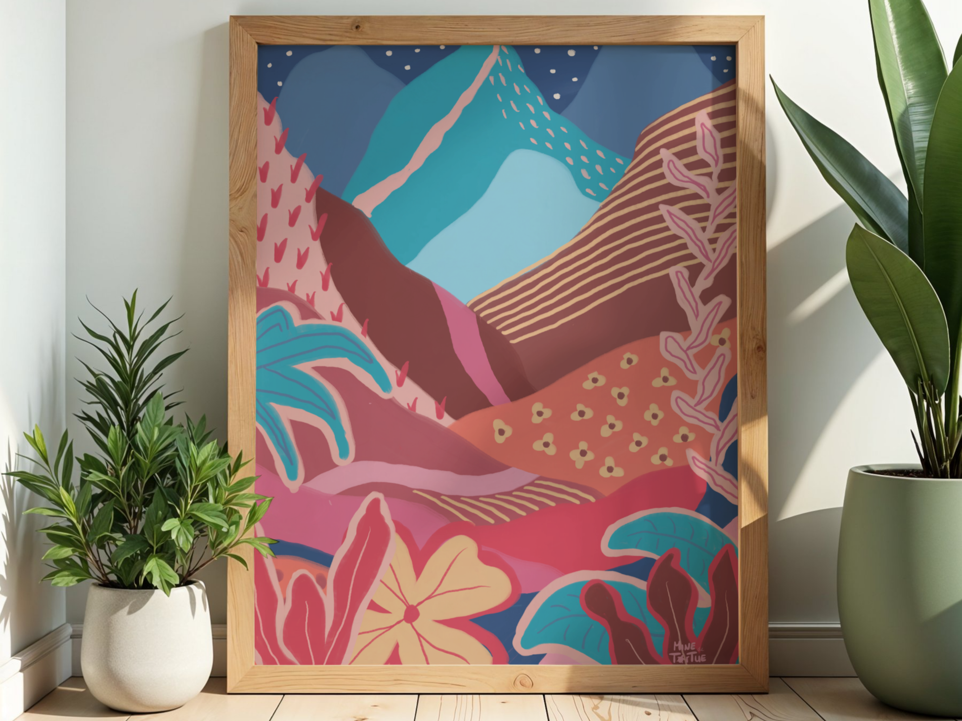 Colourful landscape poster with mountains, sun and tropical plants. Warm, layered wall art in oak frame standing on wooden floor next to plants.