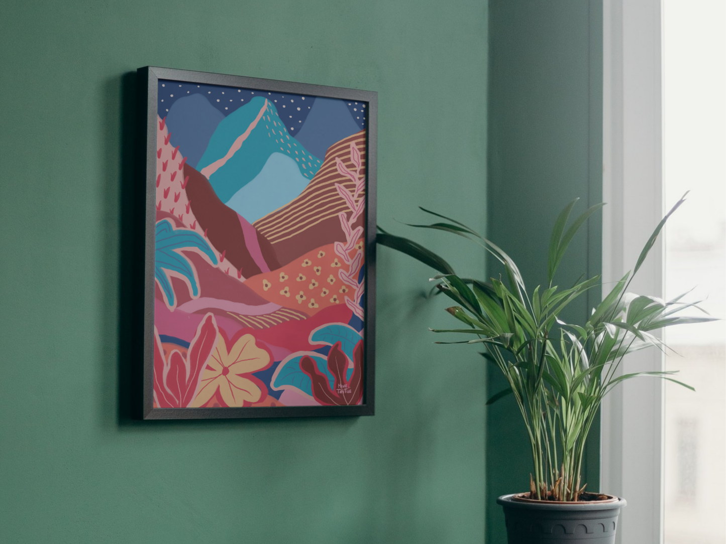 Colourful landscape poster with mountains, sun and tropical plants. Warm, layered wall art in black frame hanging on a green wall.